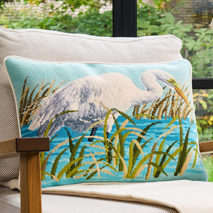 Decorative pillow with a nature scene of a swan and reeds on a chair.