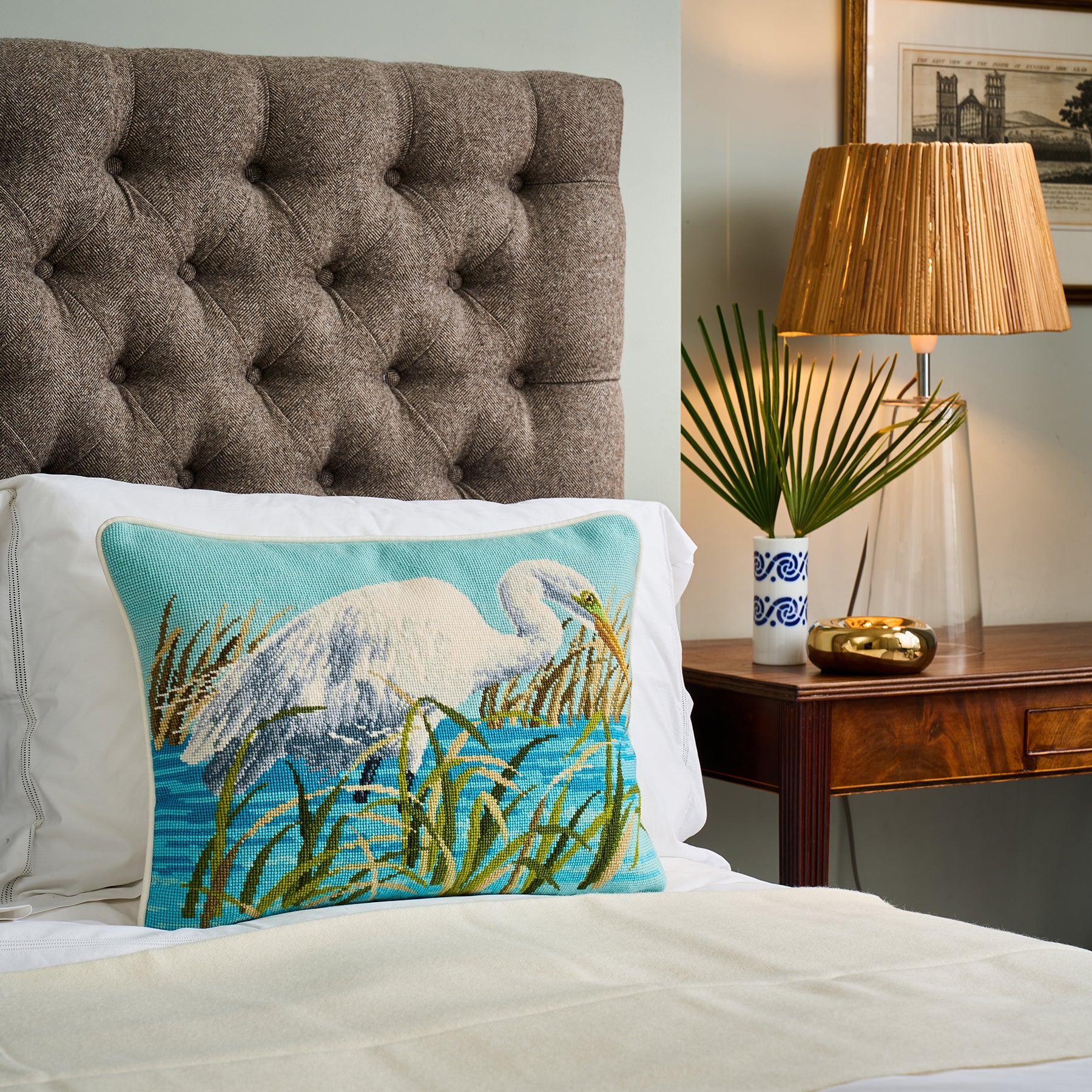 Decorative pillow with a bird design on a bed in a bedroom setting.