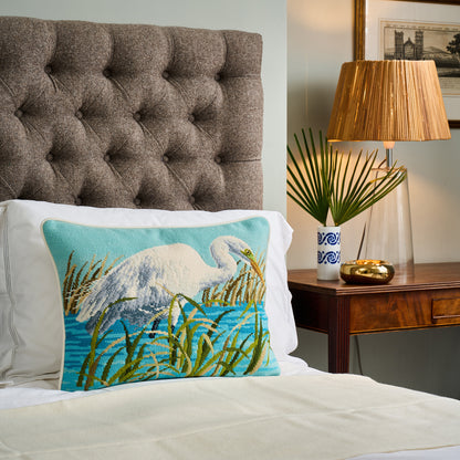 Decorative pillow with a bird design on a bed in a bedroom setting.