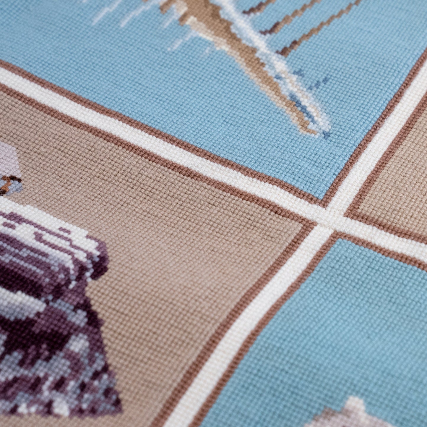 Close-up of a woven tapestry carpet with shells in light blue, tan, white, and brown.